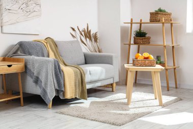 Beyaz oturma odasındaki kanepenin yanındaki sehpanın üzerinde nargile var.