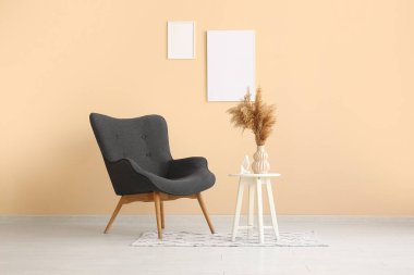 Konforlu siyah koltuk, otlar ve bej duvardaki çerçeveler