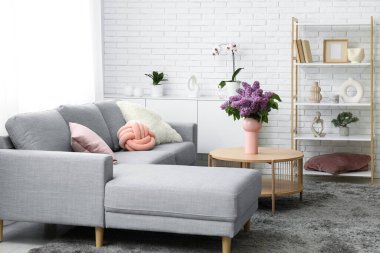 Oturma odasının güzel iç kısımları, sehpanın yanındaki sehpanın üzerinde bir buket leylak dallarıyla dolu.