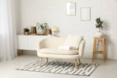 Oturma odasındaki beyaz tuğla duvarın yakınındaki çekmecelerin üzerindeki kitaplar ve bitkiler bulanık görünüyor.