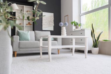Interior of modern living room with grey sofa and glass coffee table