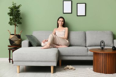 Pijamalı genç bir kadın oturma odasında kanepede dinleniyor.