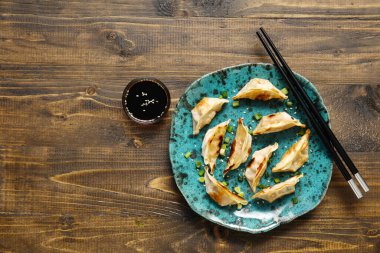 Kızarmış Japon gyoza tabağı ve ahşap arka planda soya sosu.
