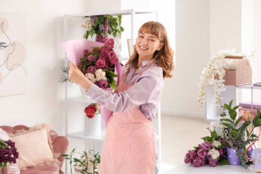 Çiçekçide güzel bir demet leylağı olan kadın çiçekçi.