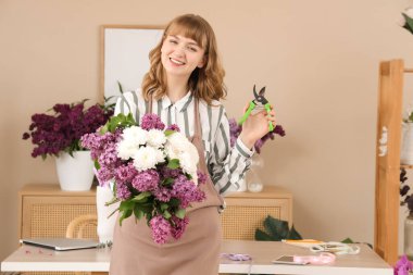Çiçekçide çiçek buketi, leylak ve kasımpatı tutan kadın.