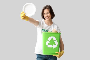 Beyaz arka planda çöp ve plastik plakalı geri dönüşüm kutusunu tutan kadın gönüllü.