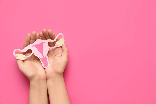 Female hands with paper uterus on pink background, closeup