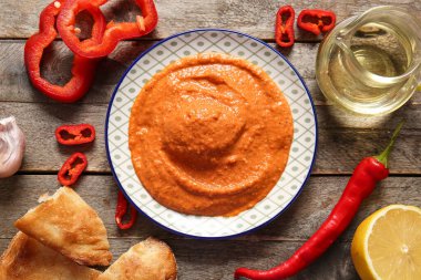 Lezzetli bir tabak muhammara ve ahşap arka planda malzemeler.