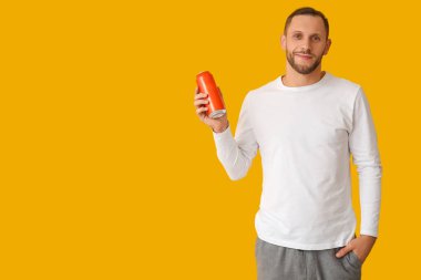 Sarı arka planda soğuk bira kutusu olan genç adam.