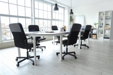 Toplantı için masa hazırlanmış modern ofisin içi.