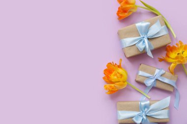 Şenlikli hediye kutuları ve pembe arka planda güzel çiçekler
