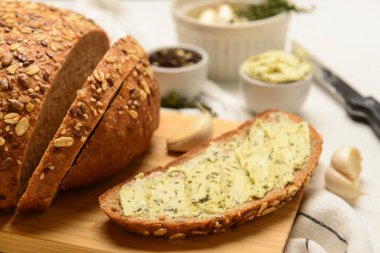 Tahta tahta ekmek dilimleri, taze tereyağı ve beyaz arka planda sarımsak.