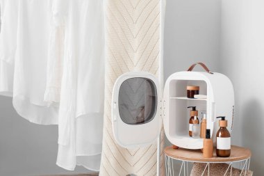 Odadaki duvarın yanındaki masada ürünlerle birlikte kozmetik buzdolabı aç