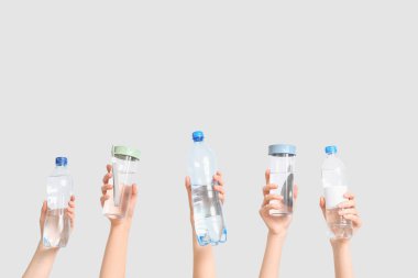 Beyaz arka planda farklı su şişeleri olan kadın eller, yakın plan.