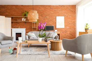 Orchid flower with seedlings and gardening tools on table in living room interior