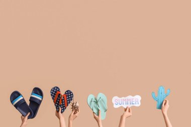 Kabuklu, kağıt kaktüslü ve bej arkaplanlı üç çift parmak arası terlik tutan eller.