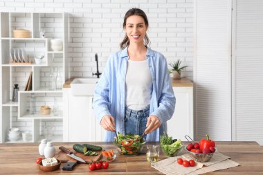 Güzel genç bayan mutfakta taze sebze salatası hazırlıyor.