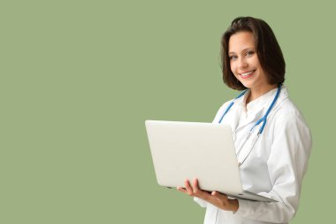 Yeşil arka planda modern dizüstü bilgisayarı olan güzel bir kadın doktor.
