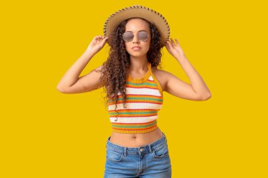 Sarı arka planda güneş gözlüklü güzel Afro-Amerikalı kadın.