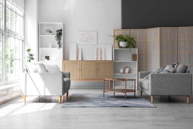 Koltukları, çekmeceleri ve tabloları olan şık bir oturma odası.