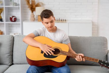 Evde gitar çalan genç çocuk