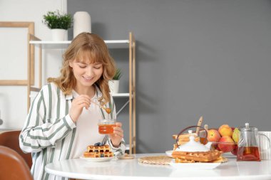 Kadın mutfaktaki tatlı waffle 'lara tatlı bal ekliyor.