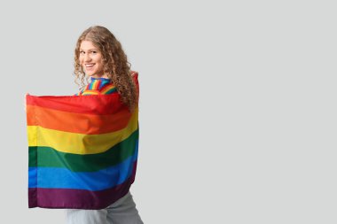Gri arkaplanda LGBT bayrağı olan güzel genç bir kadın.