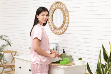 Güzel genç bir kadın banyoda aloe vera jeli yapıyor.