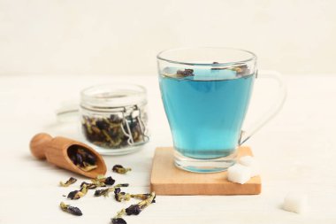 Kelebek çiçekli kepçe çay ve beyaz arka planda mavi organik çay, yakın plan.