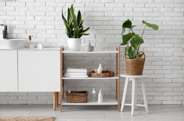 Çekmeceler ve raflar havlular ve spreylerle dolu beyaz tuğla duvarın yanındaki odada.