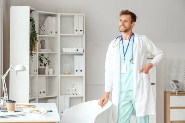 Klinikteki masanın yanında erkek doktor stajyeri.