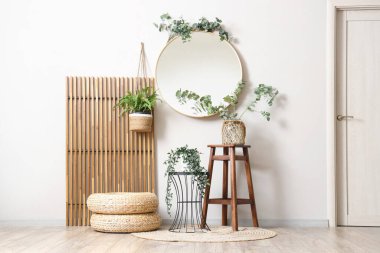 Katlanan ekran, ayna ve okaliptüs vazosu oturma odasındaki sehpanın üzerinde.