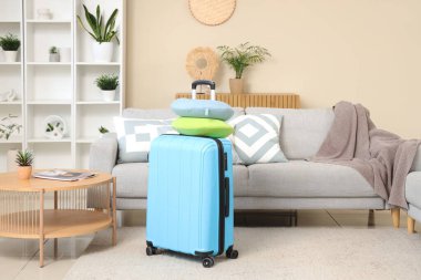 Mavi bavul ve boyun yastıkları odada. Seyahat kavramı