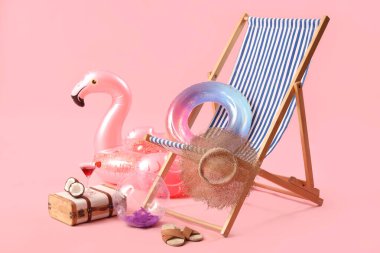 Şişirilebilir halkalar, güverte sandalyesi ve içinde hindistan cevizi olan bavul ve pembe arka planda kokteyl. Seyahat kavramı