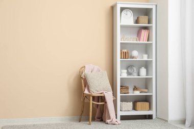 Kitaplar, vazolar ve sepetlerle raflar oturma odasındaki bej duvarın yanında.