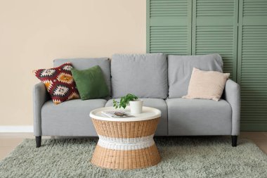 Oturma odası, rahat gri kanepe, sehpa ve katlanır ekran.