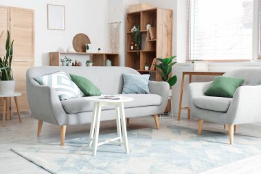 Oturma odasının içinde kanepe, koltuk ve raf üniteleri var.