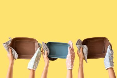 Sarı arka planda pişirme şekilleri olan eldivenli kadın eller.