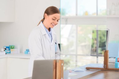 Eczanedeki tezgahın arkasındaki kadın eczacının portresi.