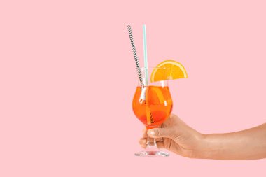 Pembe arka planda aperol sprey kokteyli olan genç bir kadın.