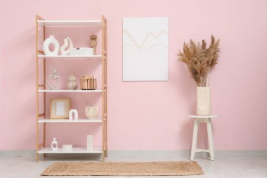Dekorlu modern raf ünitesi, otlar ve pembe duvarın yanındaki oda.