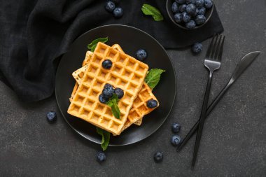 Bir tabak taze yaban mersinli Belçika waffle 'ı ve siyah arkaplanda nane şekeri