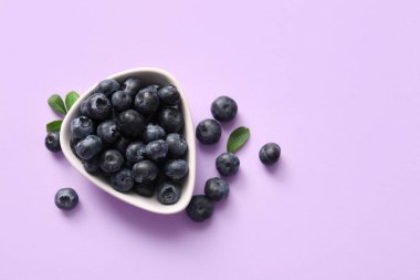 Bir kase taze olgun yaban mersini, leylak arkaplanda, yakın plan.