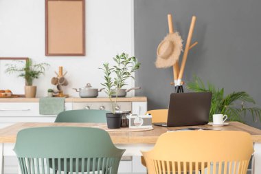 Modern dizüstü bilgisayar, ev bitkisi ve kahve şık yemek odasındaki ahşap masada.