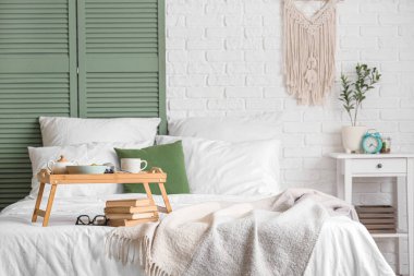 Kahvaltı tepsisi, kitap ve gözlük odada.