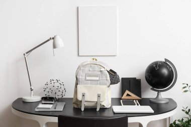 Okul gereçleri ve beyaz duvarın yanında sırt çantası olan çalışma alanı