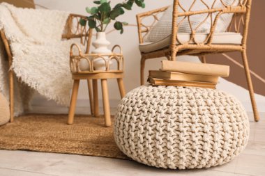 Koltuklar, vazoda dalları olan kahve masası ve odada kitaplar olan puf. Yakın çekim.