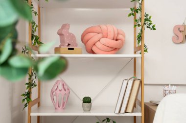 Çocuk odasında kitap ve dekor bulunan raf ünitesi.