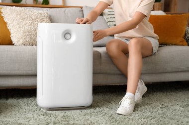 Hava nemlendiricisi olan bir kadın evdeki koltukta oturuyor.