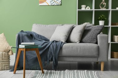 Şık oturma odasında yumuşak yastıklı gri kanepe.